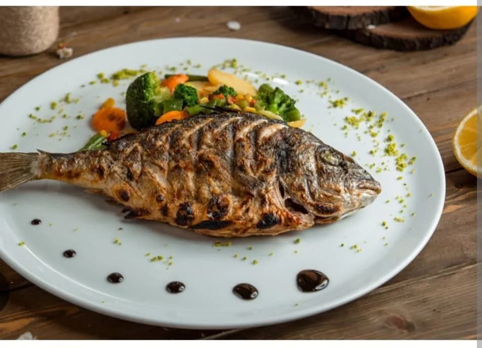 Poisson grillé entier dressé à l'assiette avec ses légumes, restaurant de Dar El Bhar